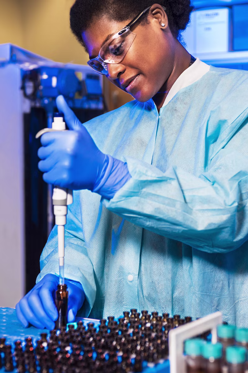 Scientist gloved hand holding brown extract bottles
